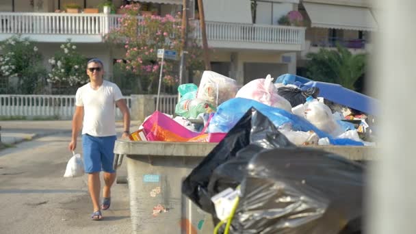 Mann wirft Mülltüte in Container - Filmmaterial, Video