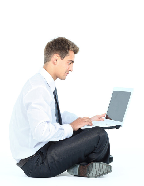 Isolated seated young businessman using a laptop - Фото, изображение