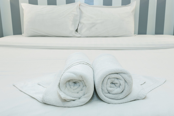 Close up de toalhas agradáveis em lençol branco com travesseiro branco
 - Foto, Imagem