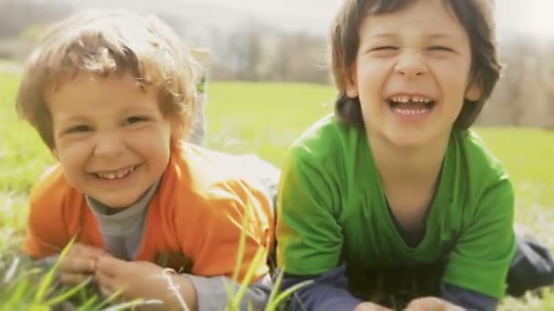 children laying down on grass and making faces - Footage, Video