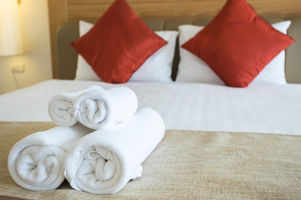 Κοντινό πλάνο συμπαθητικές πετσέτες στο λευκό σεντόνι με κόκκινο μαξιλάρι - Φωτογραφία, εικόνα