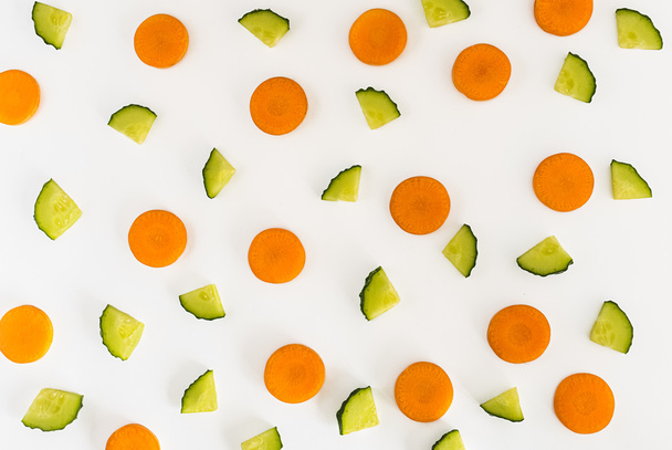 cucumbers and carrot slices on white background. Top view, Flat lay. - Fotografie, Obrázek
