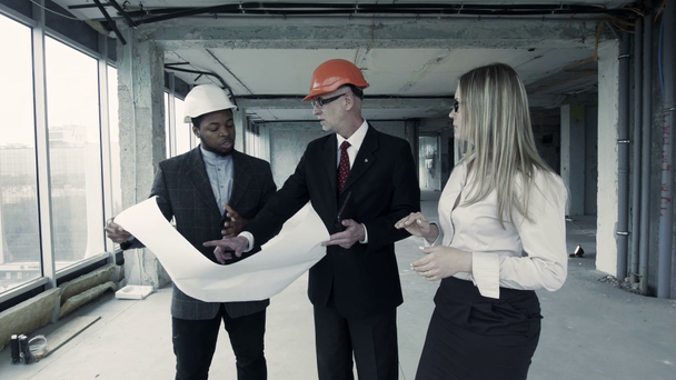 Los hombres, la mujer de traje y el casco discutir plano, comunicarse con el comprador. Ingeniero jefe constructor
 - Metraje, vídeo