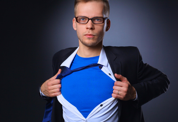 Young businessman acting like a super hero and tearing his shirt, isolated on gray background - Foto, imagen