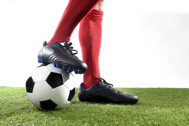 nogi piłkarzy stóp w czerwone skarpetki i czarne buty stwarzające z piłką gry na zielonej trawie skoku - Zdjęcie, obraz