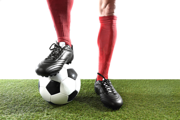 legs feet of football player in red socks and black shoes posing with the ball playing on green grass pitch - Photo, Image