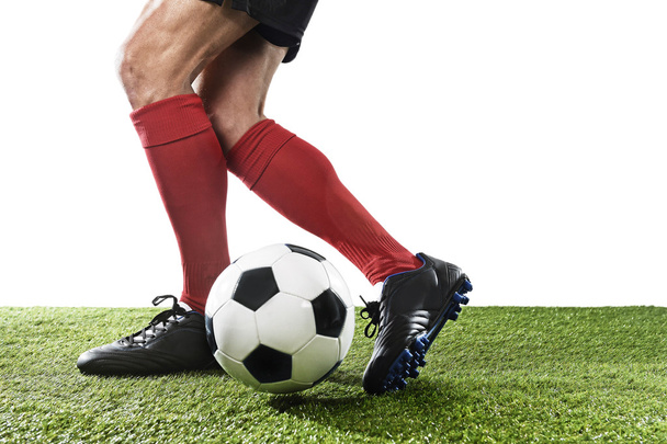 football player in red socks and black shoes running and dribbling with the ball playing on grass - Fotoğraf, Görsel