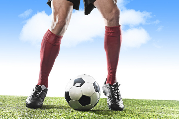 赤い靴下と黒い靴を履いたサッカー選手の足が走り、屋外でボール遊びでドリブル - 写真・画像