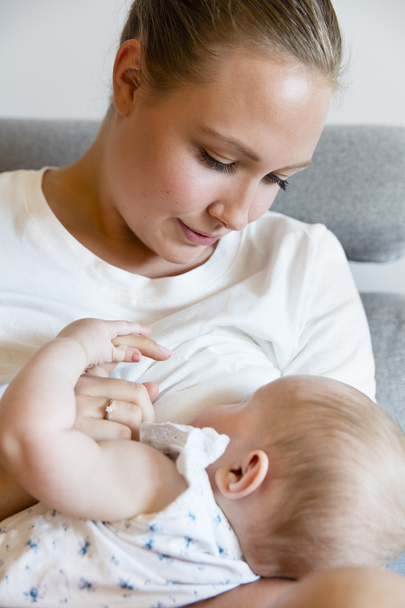 Zorgzame jonge moeder breastfeeds baby meisje - Foto, afbeelding
