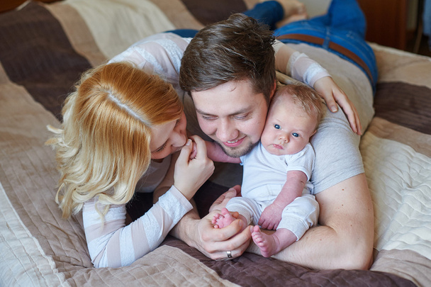 美しい幸せなカップルと彼らの赤ちゃんが一緒にベッドでリラックス - 写真・画像