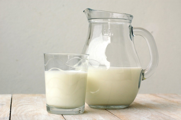 Белое молоко в стакане с кувшином на деревянном фоне
 - Фото, изображение