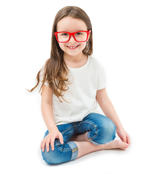 Adorable small girl is sitting down cross-legged in the lotus position barefoot. - Fotó, kép