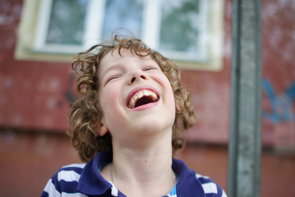 Vaalea kiharatukkainen poika nauraa iloisesti
 - Valokuva, kuva