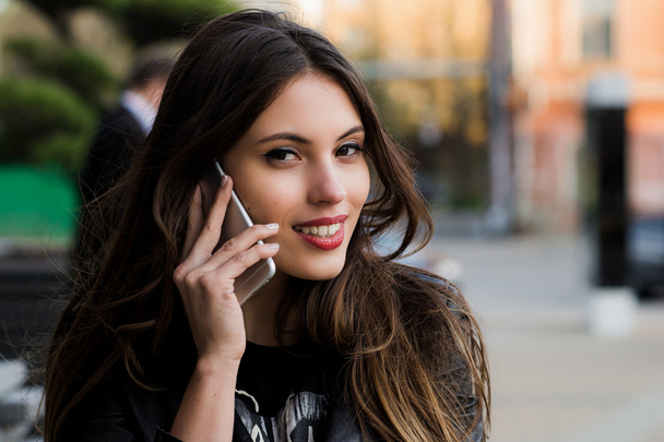 Woman phone talking. Closeup young happy beautiful smiling girl lady talking on smartphone over cityscape outdoor street background near business centre. Positive face expression human emotion - Zdjęcie, obraz