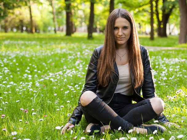 nő ül a keresztezett lábak a füvön, a parkban - Fotó, kép