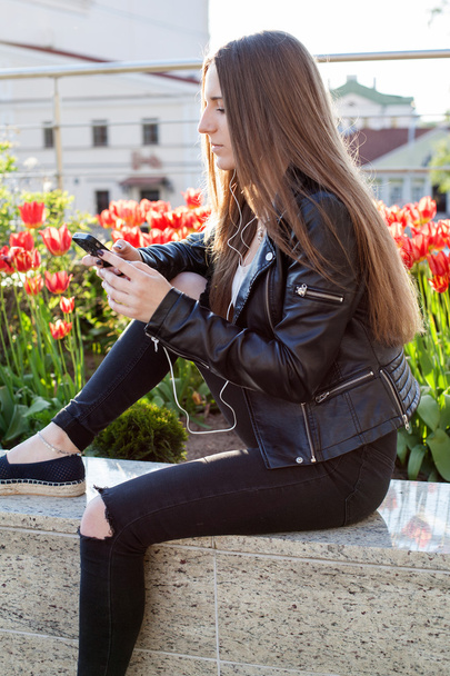  mujer en abrigo negro y jeans está sentado en el parapeto de piedra
 - Foto, imagen