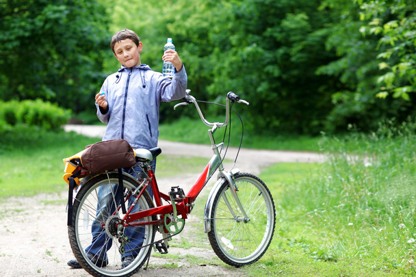 Jeune garçon avec vélo avec de l'eau claire détente en plein air
 - Photo, image