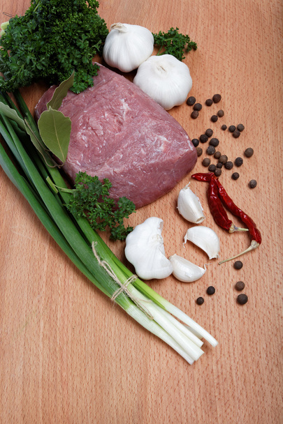 rauw vlees, groenten en kruiden geïsoleerd op een houten tafel. - Foto, afbeelding