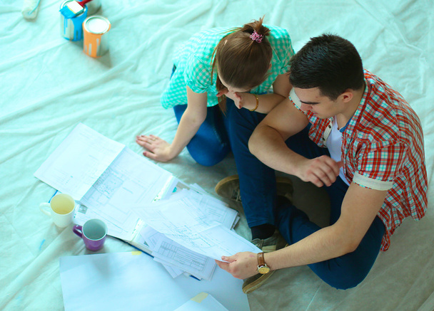 Young couple sitting on floor and calculating about they savings - Foto, Imagem
