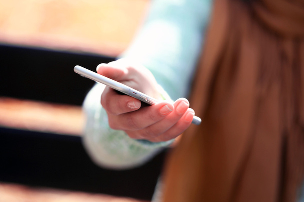  weibliche Hand hält ein Mobiltelefon  - Foto, Bild