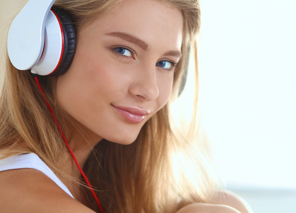 Portrait of beautiful woman in morning listening music sitting on bed at home - Foto, afbeelding