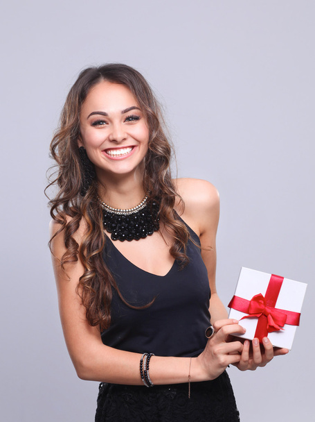 νεαρή γυναίκα ευτυχισμένη χαμόγελο κρατήστε κιβώτιο δώρων στα χέρια, απομονωμένη πέρα από το γκρι φόντο - Φωτογραφία, εικόνα