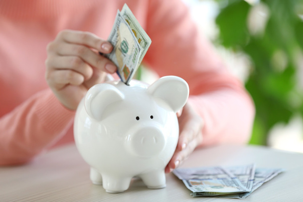 kobieta oddanie pieniędzy w piggy bank - Zdjęcie, obraz