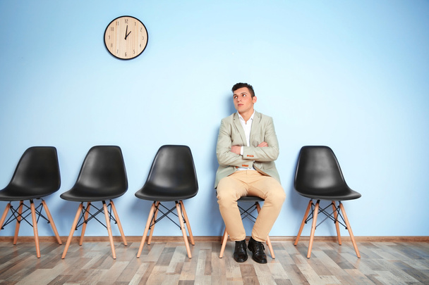 Young man in suit sitting on chair and waiting for job interview - Photo, Image
