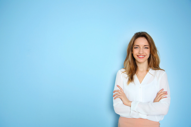 Portrait of young businesswoman against blue wall background - Foto, imagen