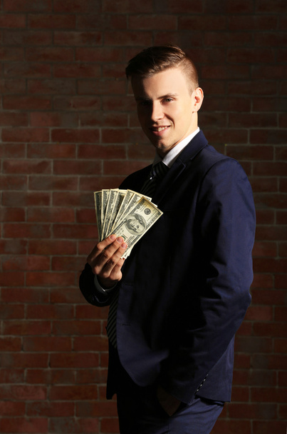 Attractive man holding fan of banknotes - 写真・画像