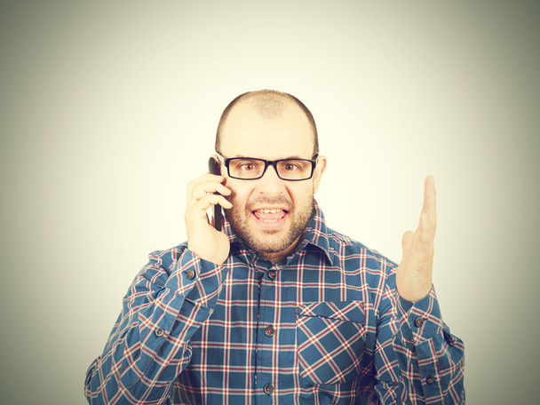 Θυμωμένος άνθρωπος σε γυαλιά φωνάζει στο τηλέφωνο. - Φωτογραφία, εικόνα