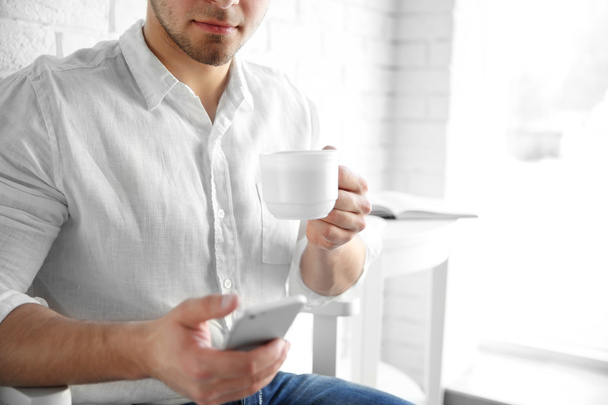 Man holding cellphone and cup  - Photo, Image