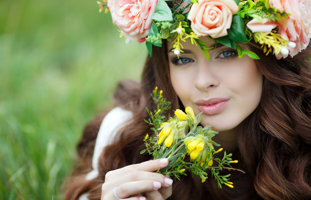 Spring portrait of a beautiful woman in a wreath of flowers - Фото, изображение