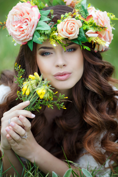 Spring portrait of a beautiful woman in a wreath of flowers - Foto, imagen