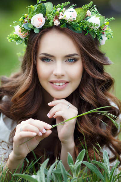 Spring portrait of a beautiful woman in a wreath of flowers - Zdjęcie, obraz