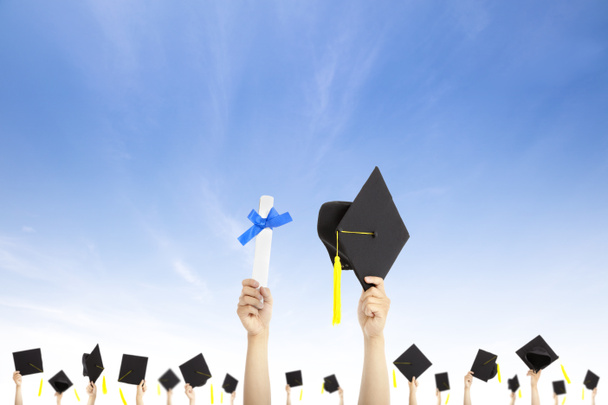 Hand hält Abschlussmütze und Diplom mit Wolkenhintergrund - Foto, Bild
