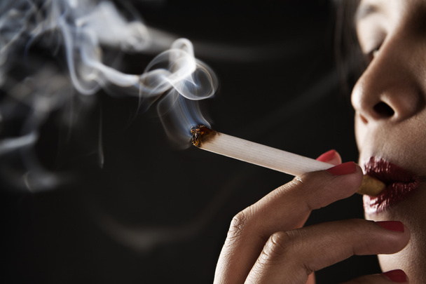 Woman smoking on dark area - Фото, изображение