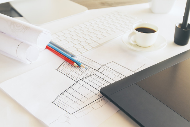 Closeup of desktop with construction sketch, graphic tablet, coffee cup and other items - Zdjęcie, obraz