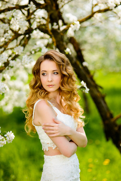 Spring beautiful girl, blonde, standing in a blooming Apple orchard . - Foto, imagen