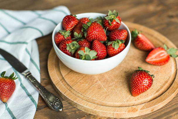 ripe strawberries on plate on wooden background - 写真・画像