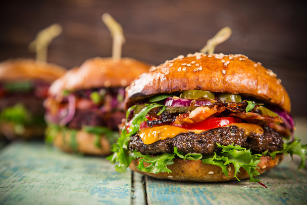 Tasty burgers on wooden table. - Fotó, kép