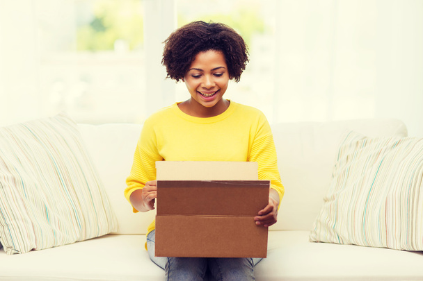 happy african young woman with parcel box at home - Foto, Imagem
