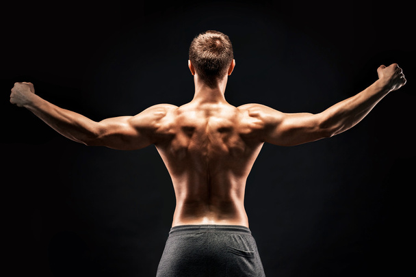 Rear view of muscular young man showing back, biceps muscles - Valokuva, kuva