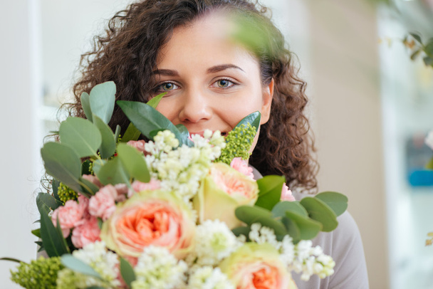 Happy woman holding bouquet of flowers and smiling - Photo, Image