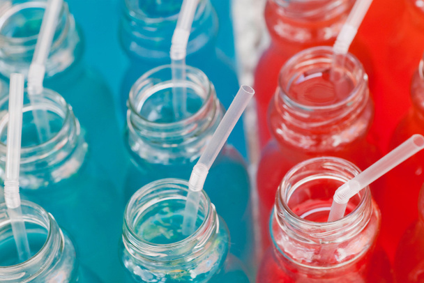 Muchas bebidas coloridas en botellas de plástico con tubos de cóctel en el bar
. - Foto, Imagen