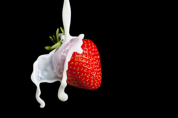 Strawberry Making A Splash. Isolated on black background. Macro photo of a strawberry in milk splashes and drops. - Foto, Imagen