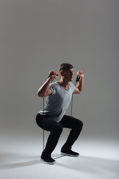 Fitness man squatting with expander - Fotografie, Obrázek