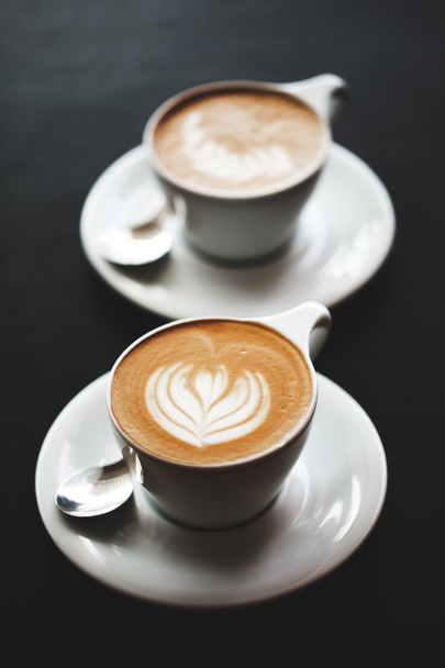 Two cups of cappuccino on black table - Photo, Image