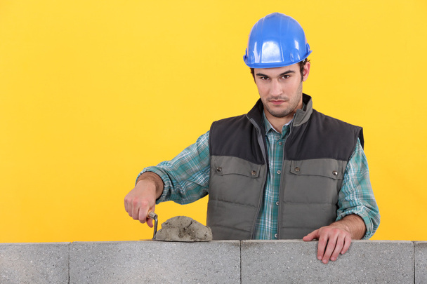 Man with trowel spreading cement on wall - Фото, зображення