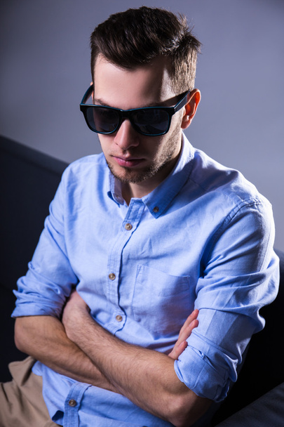 unhappy handsome man in sunglasses sitting on sofa and thinking  - Photo, Image